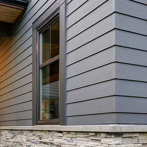 Close up view of a home with brown, vinyl siding on it